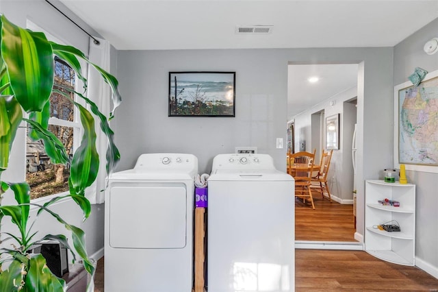 clothes washing area with washing machine and dryer and hardwood / wood-style floors