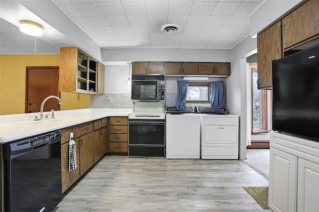 kitchen featuring kitchen peninsula, light wood-type flooring, sink, black appliances, and separate washer and dryer