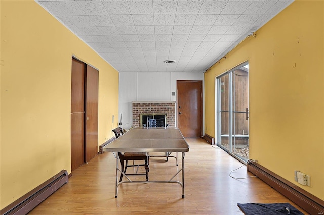 dining area with a fireplace, baseboard heating, and light hardwood / wood-style flooring