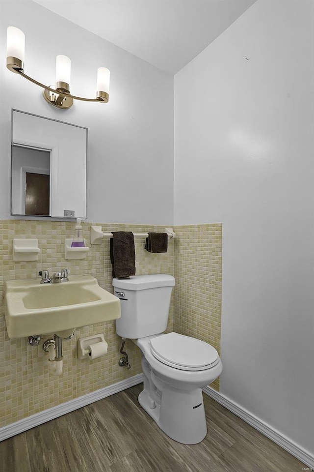 bathroom featuring hardwood / wood-style flooring, toilet, and tile walls