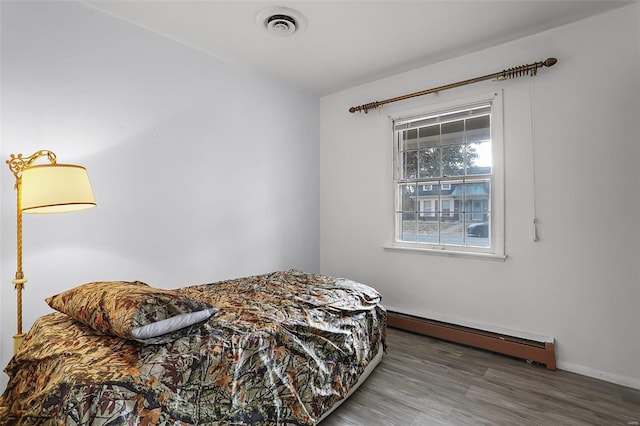 bedroom featuring hardwood / wood-style floors and baseboard heating