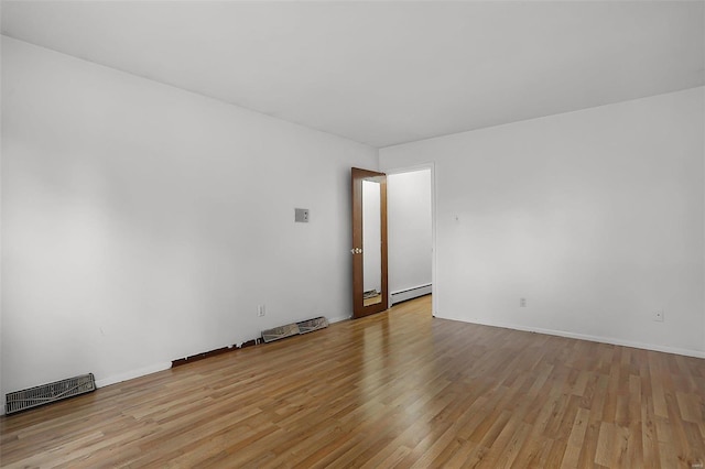 unfurnished room featuring light hardwood / wood-style flooring and a baseboard heating unit