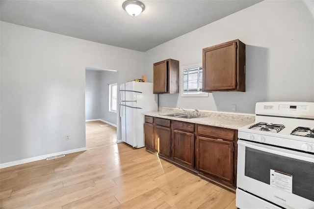 kitchen featuring light wood-type flooring, white appliances, and sink