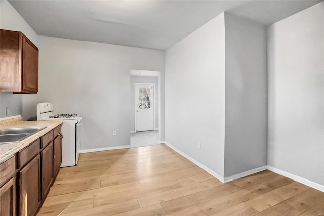 kitchen with white range oven, light hardwood / wood-style flooring, and sink