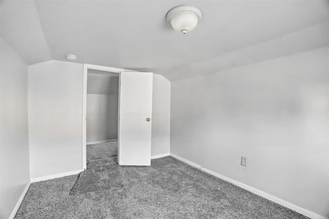 unfurnished bedroom featuring dark colored carpet, lofted ceiling, and a closet