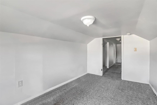 additional living space featuring dark colored carpet and vaulted ceiling