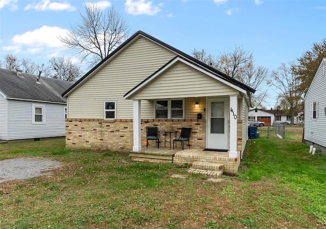 back of property with a lawn and a porch