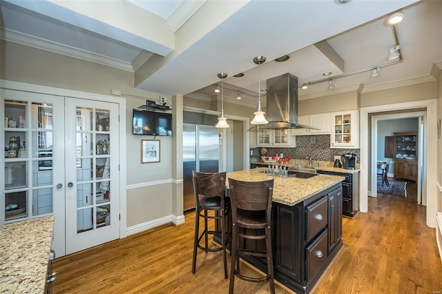 kitchen with a center island, light stone counters, island exhaust hood, high end fridge, and white cabinets