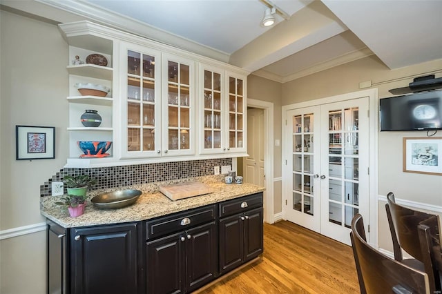 kitchen featuring backsplash, light stone counters, crown molding, light hardwood / wood-style flooring, and white cabinets