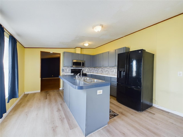 kitchen with black fridge with ice dispenser, vaulted ceiling, sink, light hardwood / wood-style flooring, and an island with sink