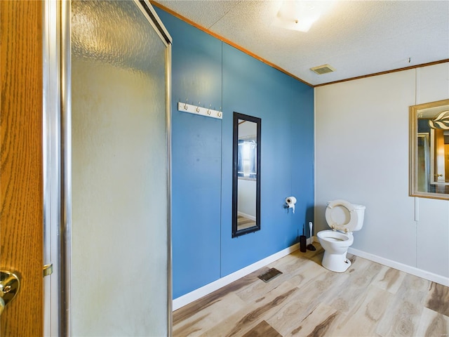 bathroom featuring hardwood / wood-style floors, toilet, ornamental molding, and a textured ceiling