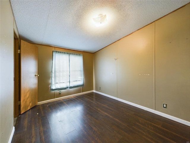 spare room featuring dark hardwood / wood-style floors and a textured ceiling