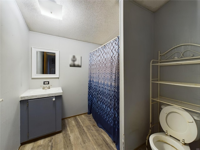 bathroom featuring a shower with shower curtain, vanity, a textured ceiling, wood-type flooring, and toilet