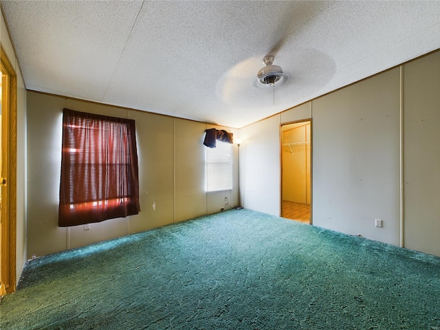 carpeted empty room with ceiling fan and a textured ceiling