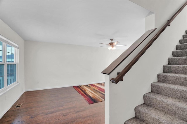 staircase with wood-type flooring and ceiling fan