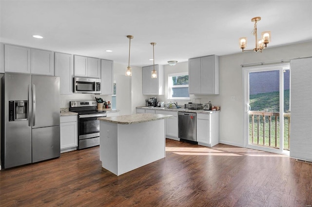 kitchen featuring decorative light fixtures, a center island, stainless steel appliances, and dark wood-type flooring