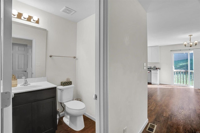 bathroom with hardwood / wood-style flooring, vanity, toilet, and a chandelier