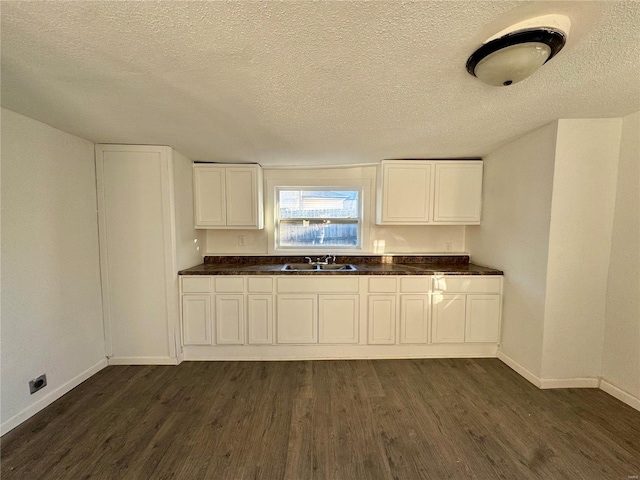 kitchen featuring dark hardwood / wood-style flooring, sink, a textured ceiling, and white cabinets