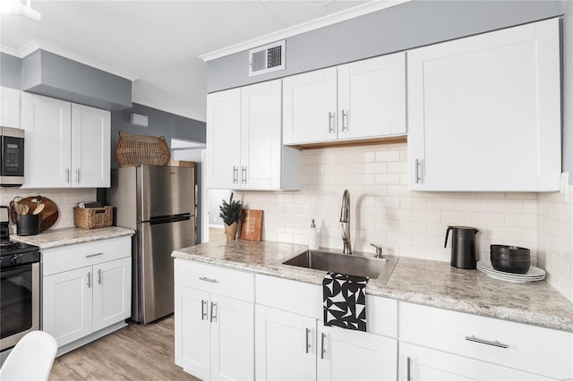 kitchen with sink, light hardwood / wood-style flooring, tasteful backsplash, white cabinetry, and stainless steel appliances