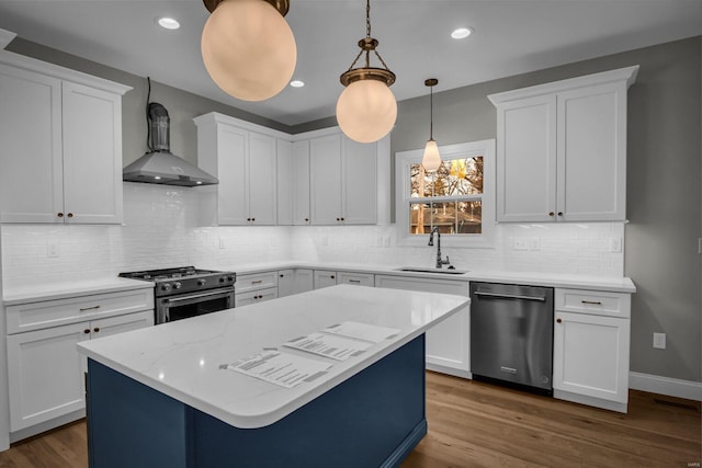 kitchen with sink, stainless steel appliances, white cabinetry, and wall chimney range hood