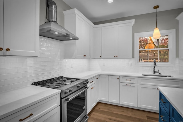 kitchen with white cabinets, sink, high end stainless steel range oven, wall chimney exhaust hood, and dark hardwood / wood-style flooring