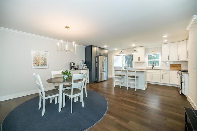 dining area featuring dark hardwood / wood-style flooring, sink, crown molding, and a chandelier