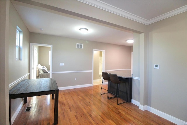 interior space featuring light hardwood / wood-style floors, crown molding, and a breakfast bar area