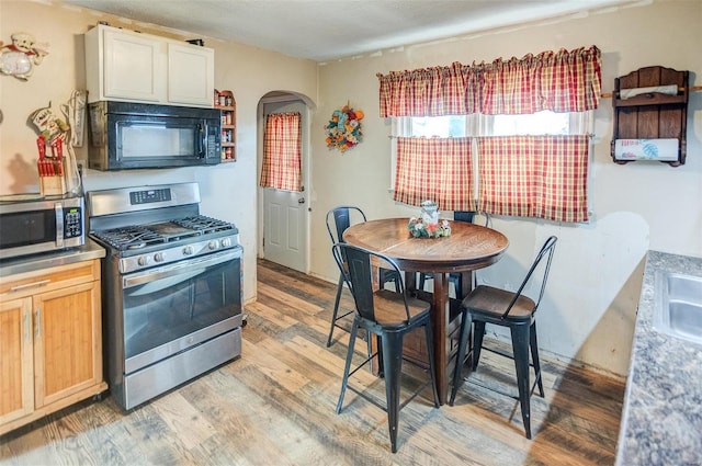 kitchen featuring light wood-type flooring, light brown cabinetry, sink, and appliances with stainless steel finishes