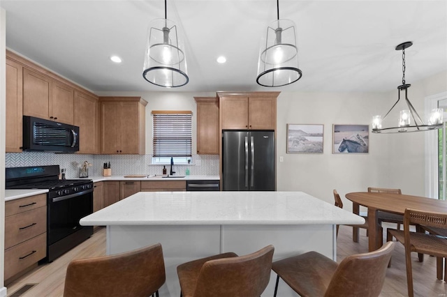 kitchen featuring decorative light fixtures, black appliances, and a kitchen island