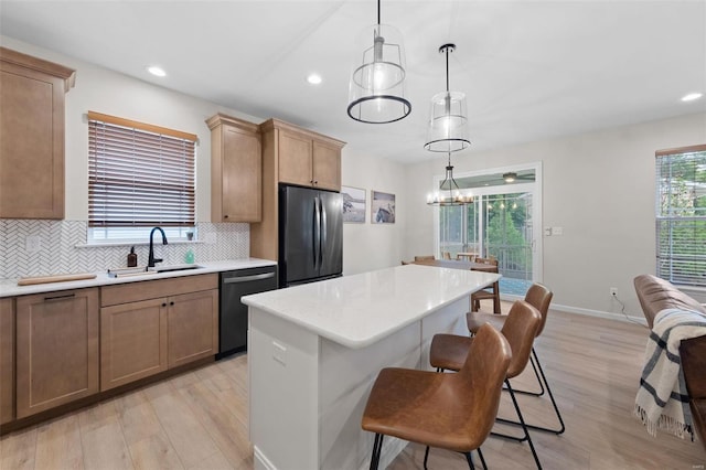 kitchen featuring sink, decorative light fixtures, stainless steel refrigerator, dishwasher, and a kitchen island