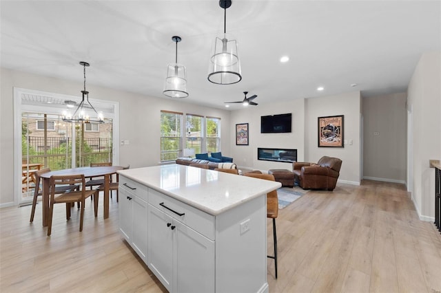 kitchen with a center island, pendant lighting, white cabinets, and light wood-type flooring