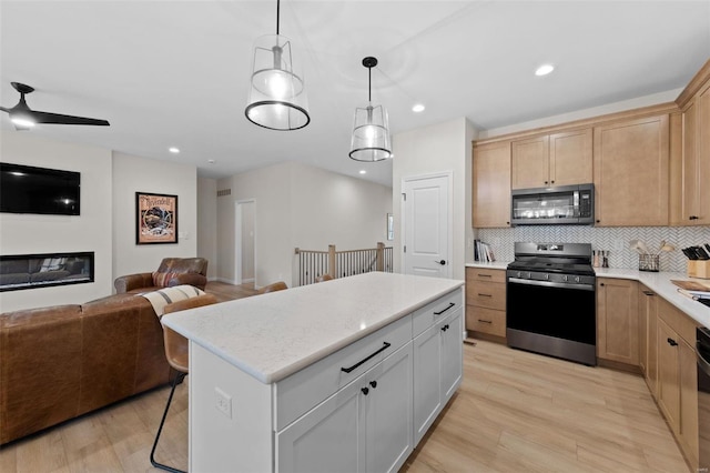 kitchen with pendant lighting, white cabinets, backsplash, a center island, and stainless steel appliances