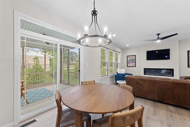 dining room with ceiling fan with notable chandelier and light hardwood / wood-style flooring