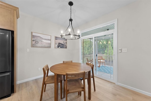 dining space with light hardwood / wood-style flooring and a chandelier