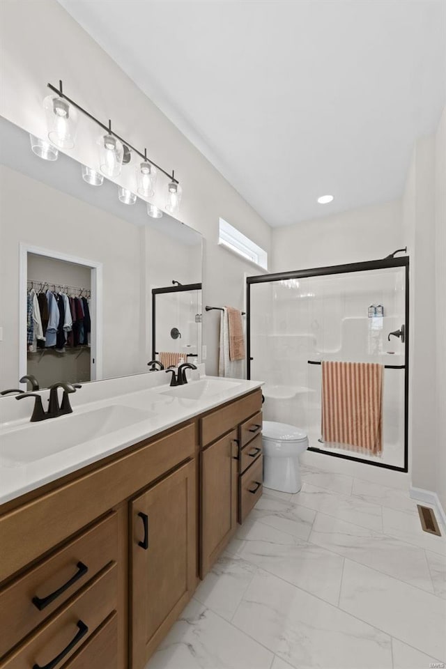 bathroom with a shower with door, vanity, and toilet