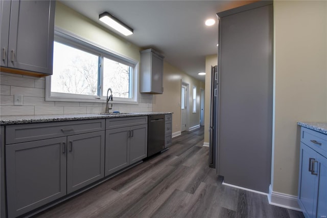 kitchen featuring backsplash, stainless steel dishwasher, gray cabinetry, sink, and dark hardwood / wood-style floors