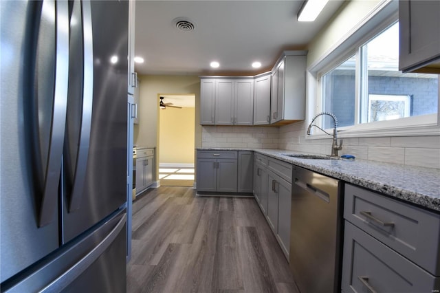 kitchen with backsplash, sink, dark hardwood / wood-style floors, gray cabinets, and appliances with stainless steel finishes