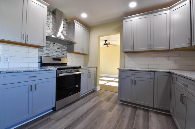 kitchen with stainless steel range, dark hardwood / wood-style floors, tasteful backsplash, and wall chimney range hood