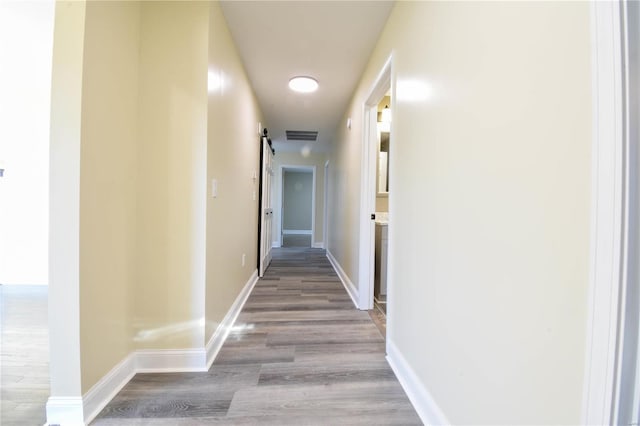 hallway with a barn door and light wood-type flooring