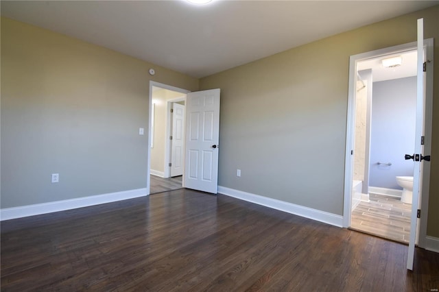 unfurnished bedroom with dark hardwood / wood-style floors and ensuite bath