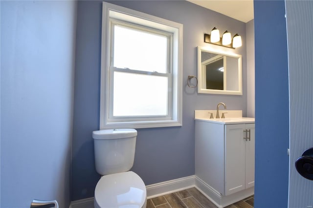 bathroom with a wealth of natural light, toilet, vanity, and hardwood / wood-style flooring