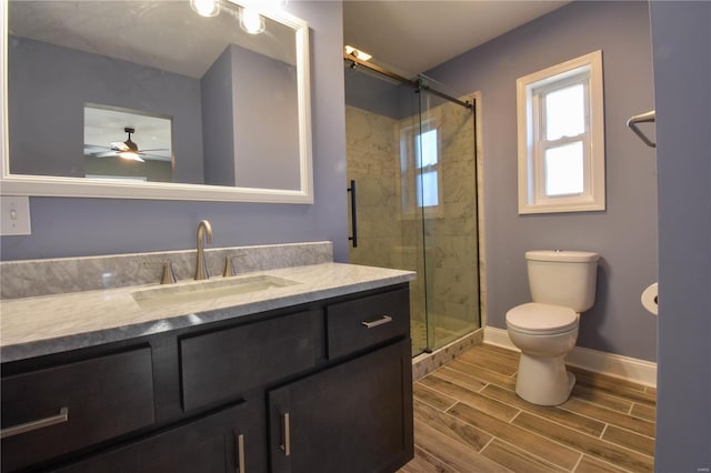 bathroom featuring walk in shower, vanity, ceiling fan, hardwood / wood-style floors, and toilet