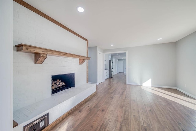 unfurnished living room featuring hardwood / wood-style floors and a brick fireplace