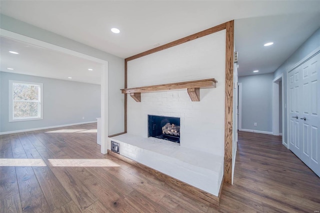 unfurnished living room featuring dark hardwood / wood-style flooring and a brick fireplace