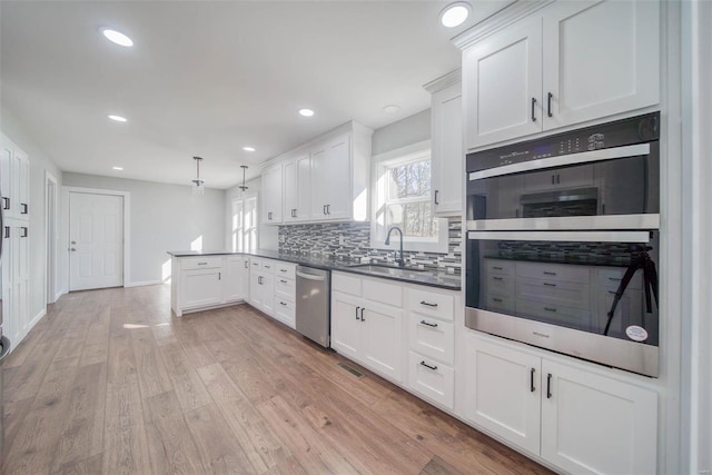 kitchen featuring hanging light fixtures, stainless steel appliances, a wealth of natural light, and light hardwood / wood-style floors