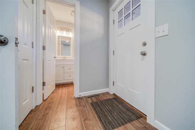 doorway to outside featuring sink and light hardwood / wood-style flooring