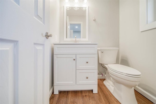 bathroom with hardwood / wood-style flooring, vanity, and toilet