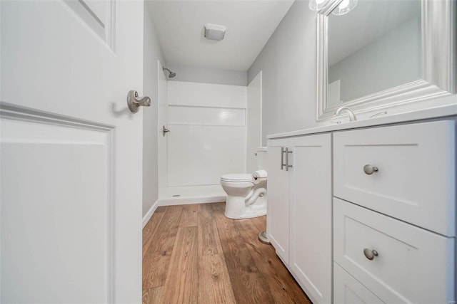 bathroom with toilet, vanity, wood-type flooring, and walk in shower