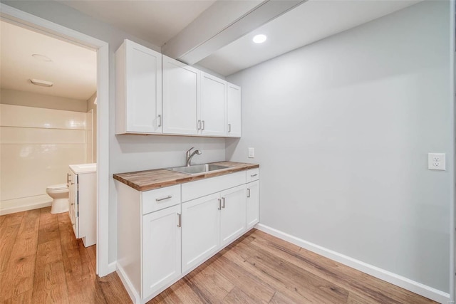 kitchen featuring white cabinets, butcher block countertops, light hardwood / wood-style floors, and sink