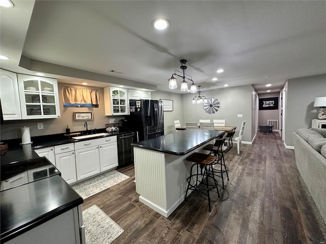 kitchen featuring sink, a center island, dark wood-type flooring, and black appliances